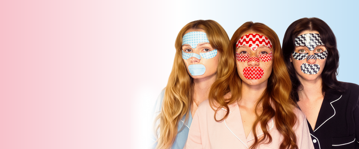 Three women wearing patterned eye masks against a pink and blue gradient background