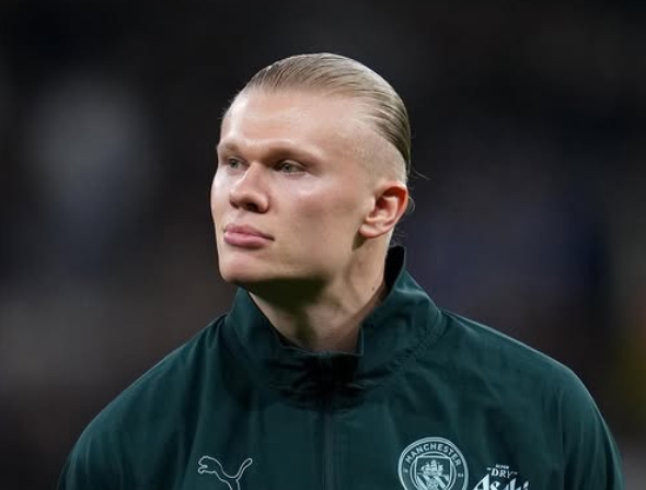Erling Haaland With a sweater on, stands on a football pitch