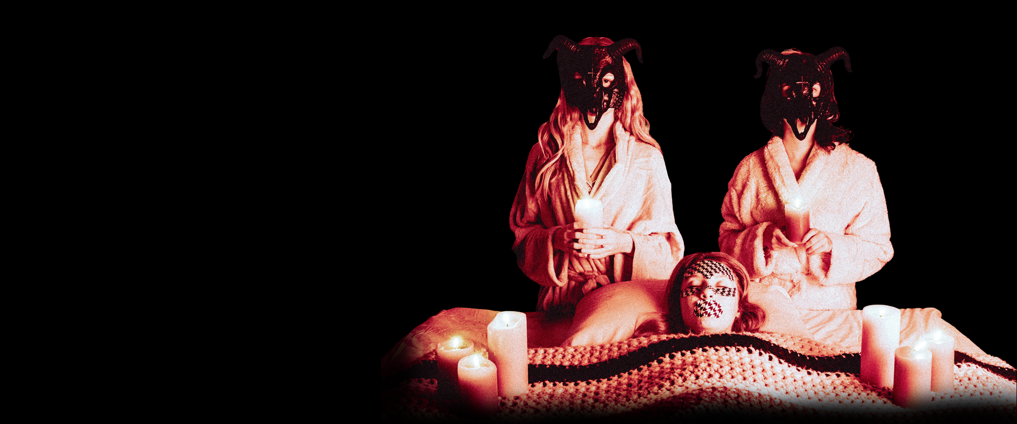 Spooky women stand above another woman sleeping with mouth tape on.